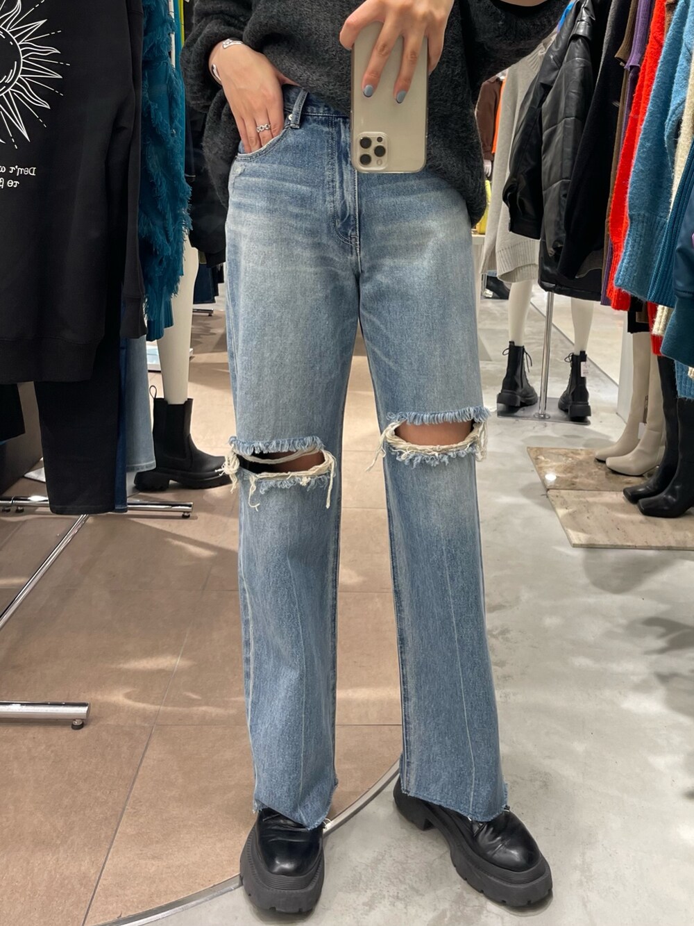 グレー系のニット/セーター、ブラック系のブーツ、ブルー系のデニムパンツを着用したレディースの秋コーディネートの5枚目の写真