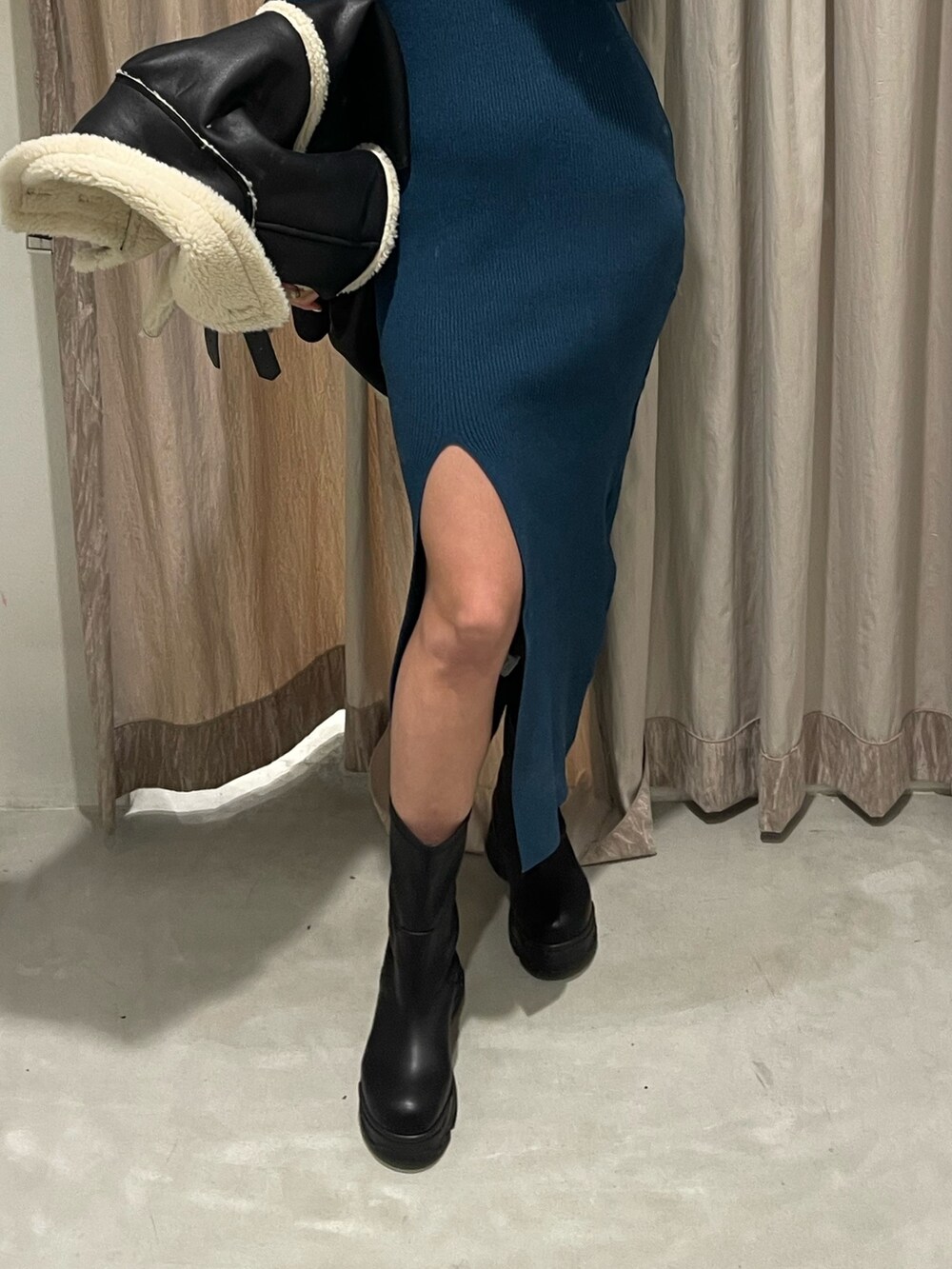 ブラック系のブルゾン、ブルー系のワンピース、ブラック系のブーツを着用したレディースの冬コーディネートの5枚目の写真