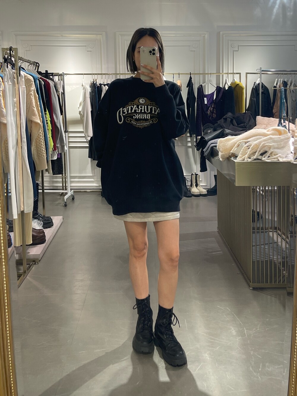 ブラック系のスウェット、ホワイト系のスカート、ブラック系のブーツを着用したレディースの秋コーディネートの6枚目の写真