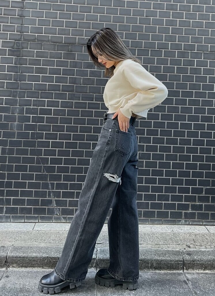 ブラック系のデニムパンツ、ブラック系のブーツ、ホワイト系のスウェットを着用したレディースの冬コーディネートの3枚目の写真