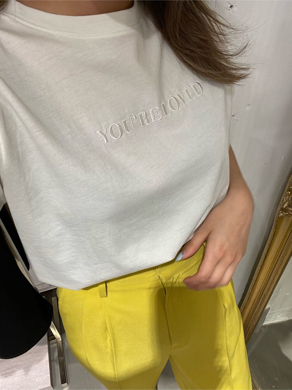 イエロー系のスラックス、ホワイト系のTシャツ/カットソー、ホワイト系のサンダルを着用したレディースの春コーディネートの5枚目の写真