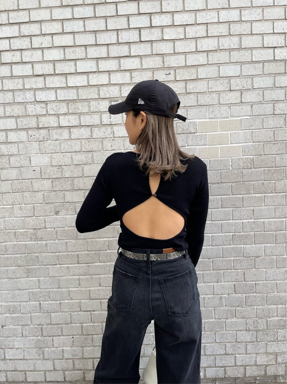 ブラック系のデニムパンツ、ブラック系のニット/セーター、ホワイト系のショルダーバッグを着用したレディースの冬コーディネートの9枚目の写真