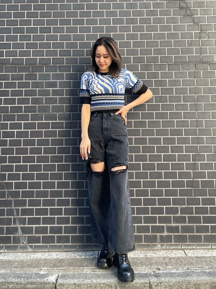 ブラック系のデニムパンツ、ブルー系のニット/セーター、ブラック系のブーツを着用したレディースの春コーディネートの2枚目の写真