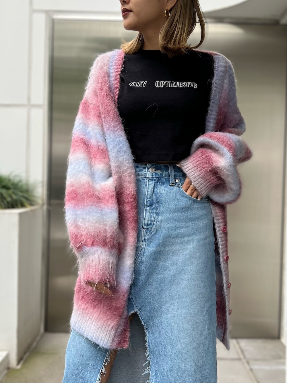 ブラック系のTシャツ/カットソー、ブルー系のデニムスカート、ピンク系のカーディガン/ボレロを着用したレディースの秋コーディネートの3枚目の写真