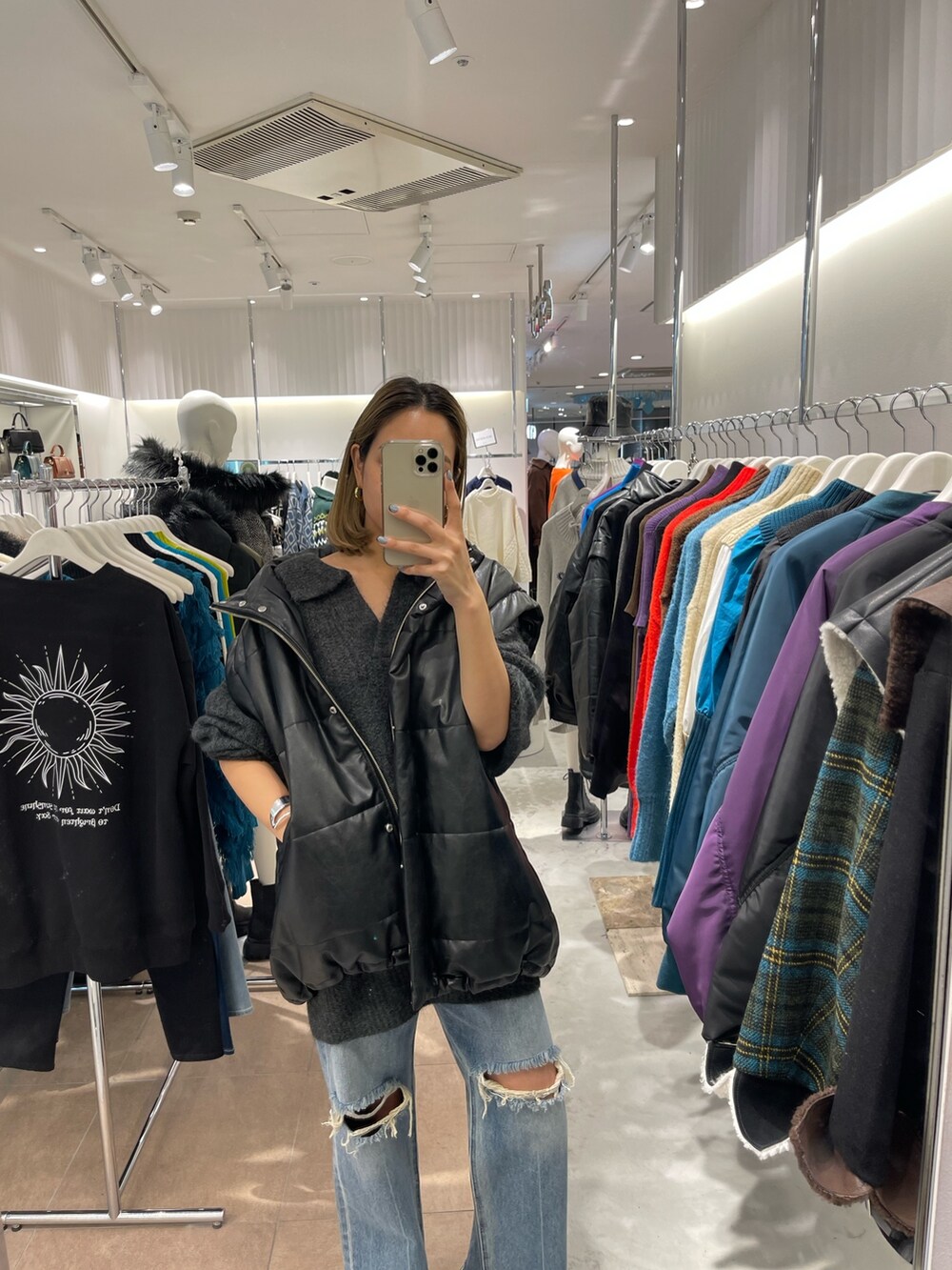 グレー系のニット/セーター、ブラック系のブーツ、ブルー系のデニムパンツを着用したレディースの秋コーディネートの6枚目の写真