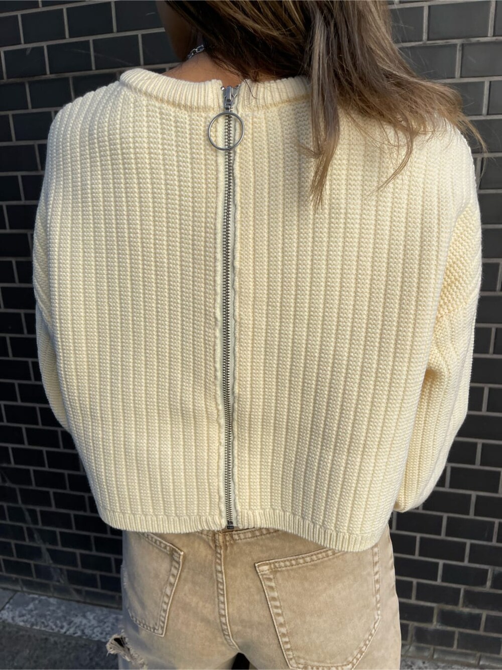 ベージュ系のデニムパンツ、ブラウン系のショルダーバッグ、ホワイト系のニット/セーターを着用したレディースの冬コーディネートの4枚目の写真