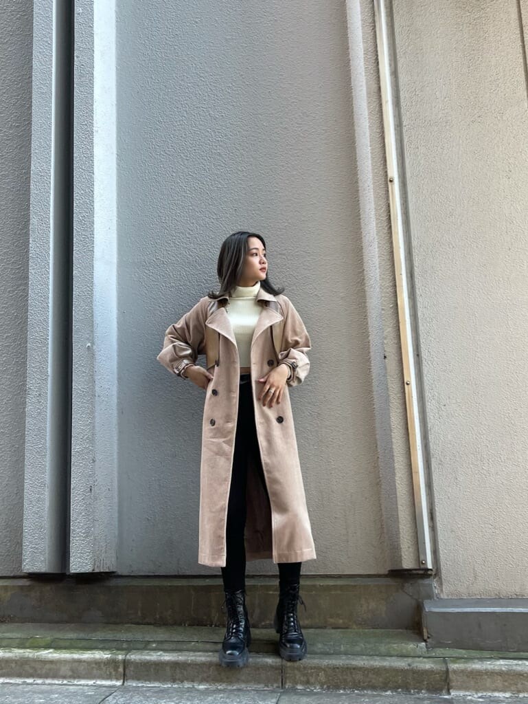 ブラック系のデニムパンツ、ベージュ系のトレンチコート、ホワイト系のニット/セーターを着用したレディースの秋コーディネートの2枚目の写真