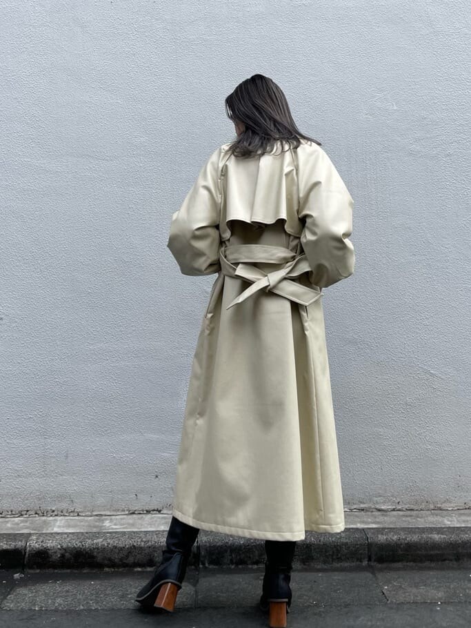 ブラック系のニット/セーター、ホワイト系のトレンチコート、ブラック系のブーツを着用したレディースの冬コーディネートの2枚目の写真