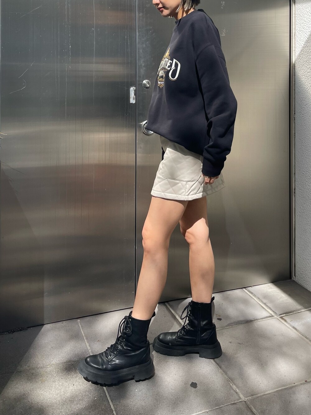 ブラック系のスウェット、ホワイト系のスカート、ブラック系のブーツを着用したレディースの秋コーディネートの2枚目の写真