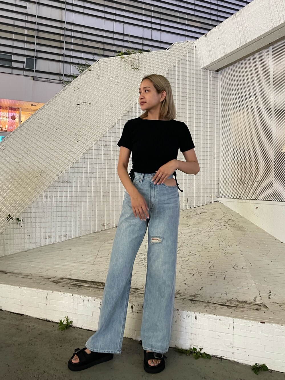 ブルー系のデニムパンツ、ブラック系のTシャツ/カットソー、ブラック系のサンダルを着用したレディースの夏コーディネートの2枚目の写真