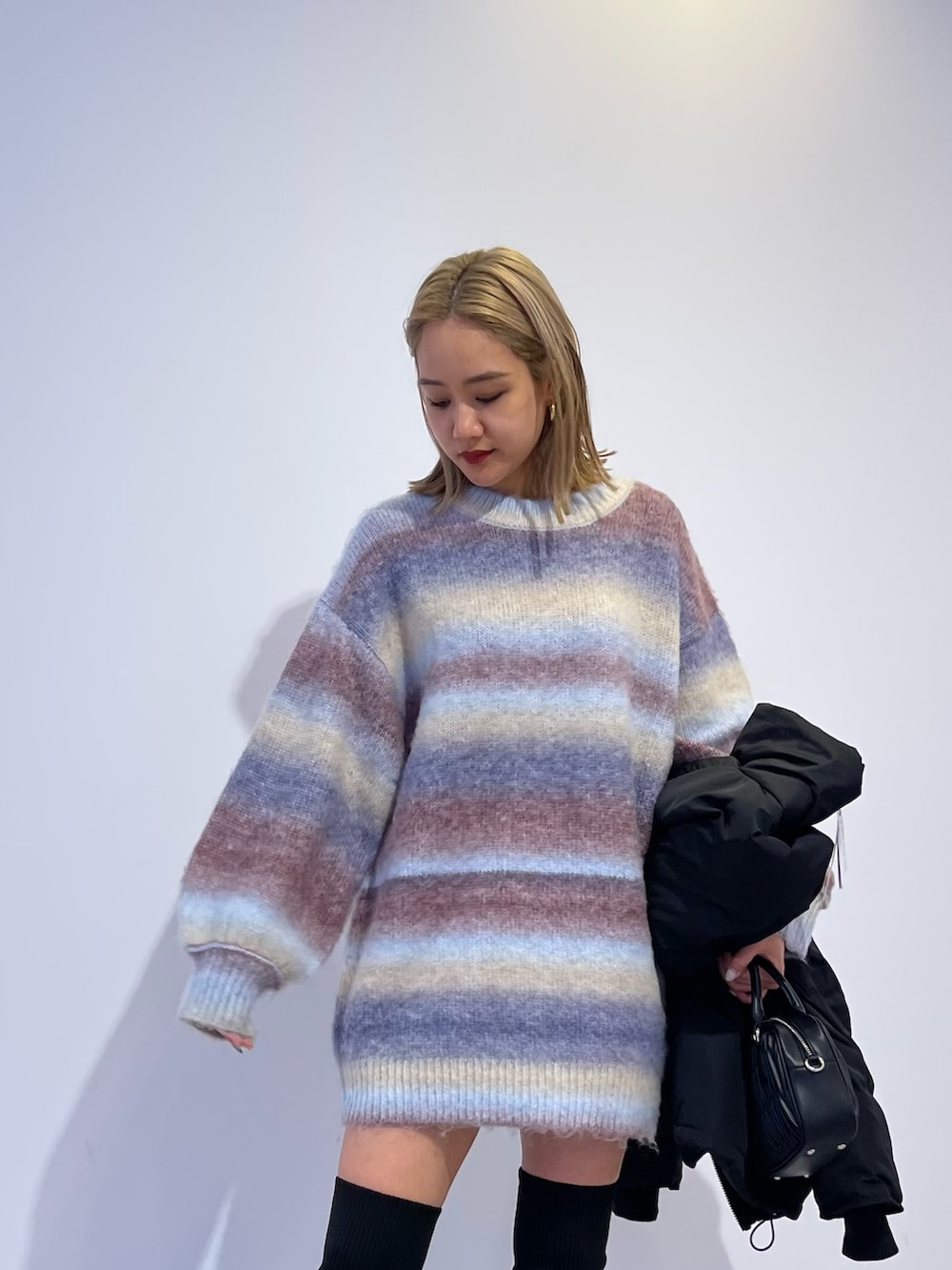 パープル系のニット/セーター、ブラック系のブーツ、ブラック系のダウンジャケット/コートを着用したレディースの冬コーディネートの5枚目の写真