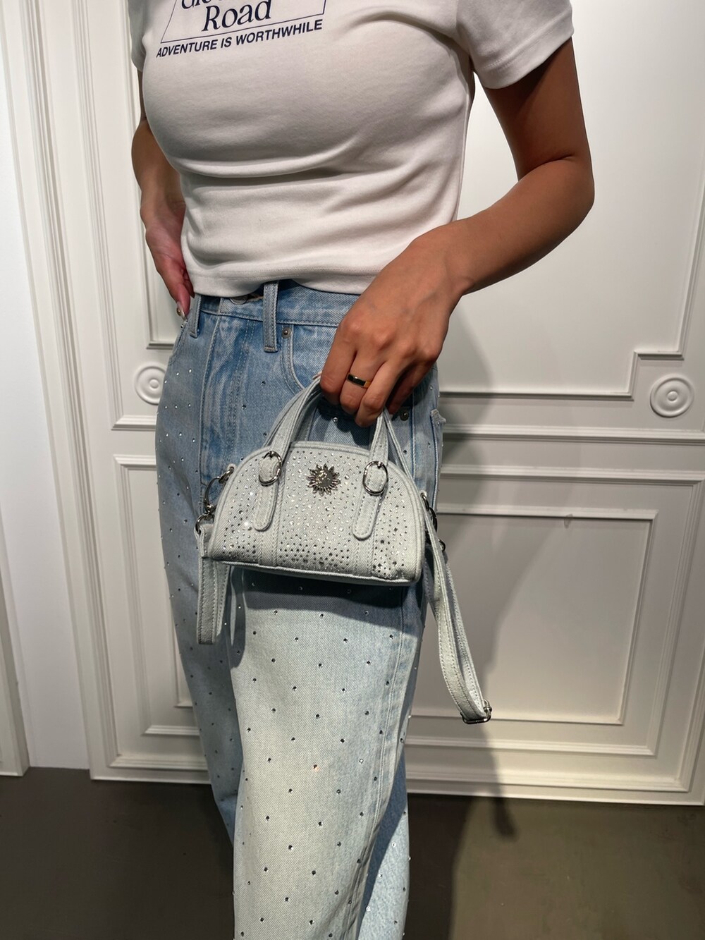 ブルー系のデニムパンツ、ブラック系のサンダル、ホワイト系のTシャツ/カットソーを着用したレディースの夏コーディネートの6枚目の写真