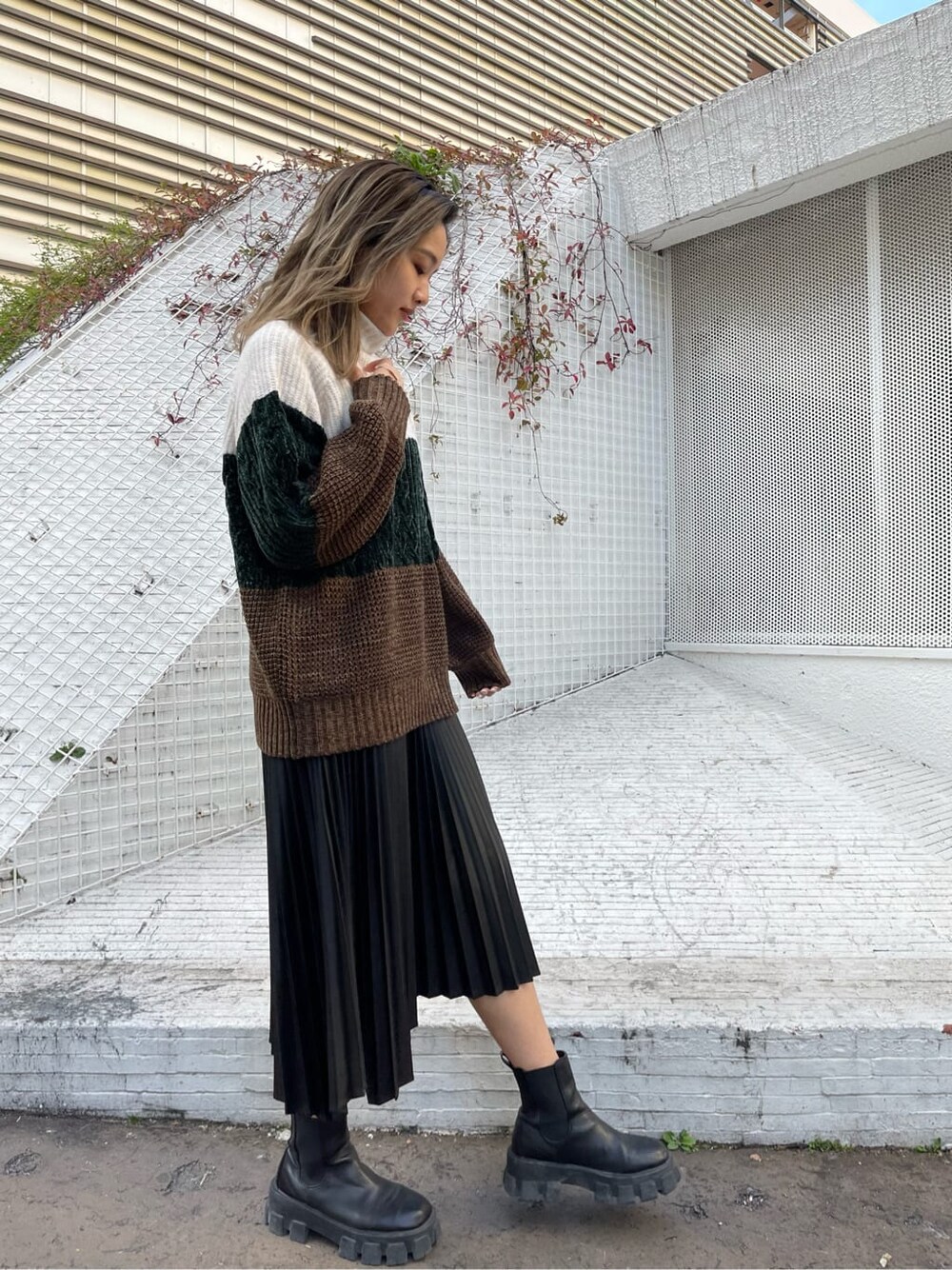 ブラック系のブーツ、ホワイト系のニット/セーター、ブラック系のスカートを着用したレディースの秋コーディネートの2枚目の写真