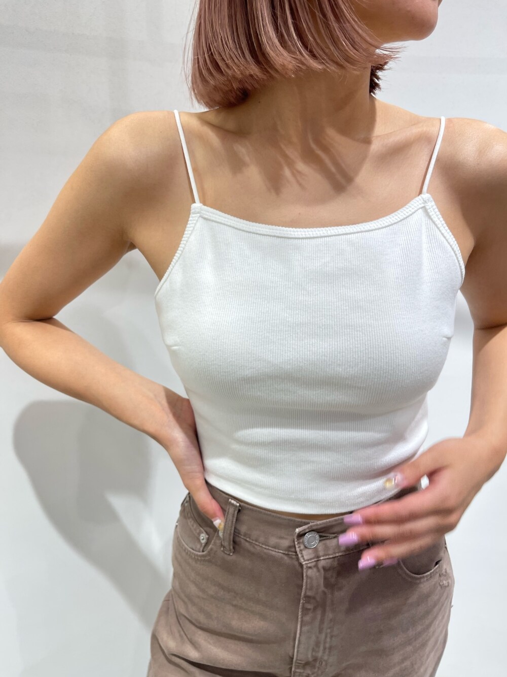 ブラック系のサンダル、ブラウン系のデニムパンツ、ホワイト系のキャミソールを着用したレディースの夏コーディネートの6枚目の写真