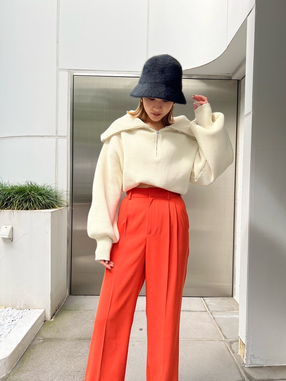 オレンジ系のスラックス、ホワイト系のニット/セーター、ブラック系のローファーを着用したレディースの秋コーディネートの4枚目の写真