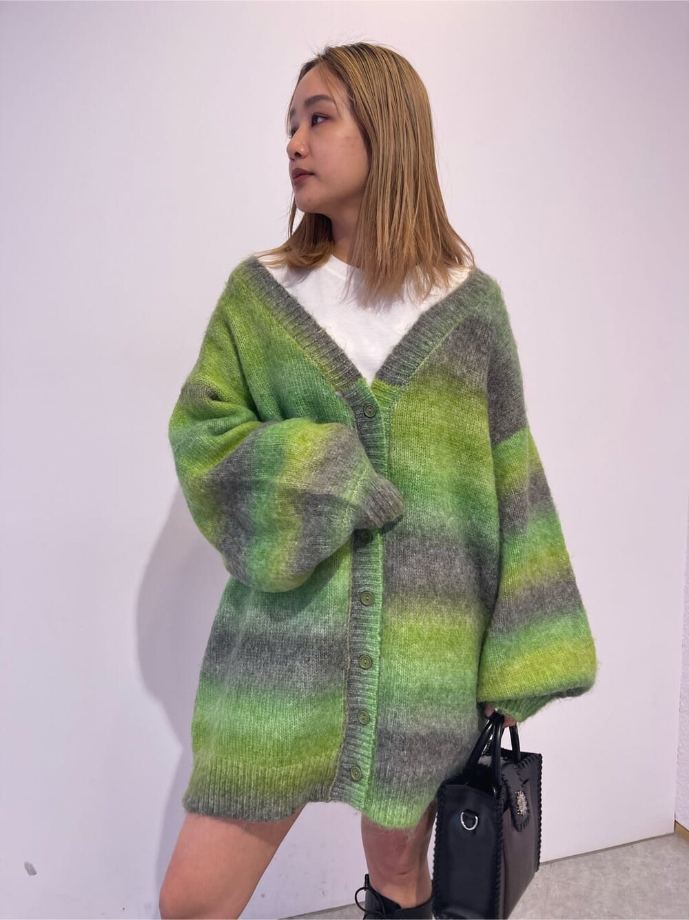 ブラック系のブーツ、ブラック系のショルダーバッグ、グリーン系のカーディガン/ボレロを着用したレディースの秋コーディネートの4枚目の写真