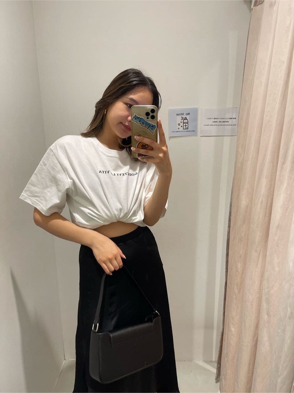ブラック系のショルダーバッグ、ホワイト系のTシャツ/カットソー、ブラック系のスカートを着用したレディースの春コーディネートの7枚目の写真