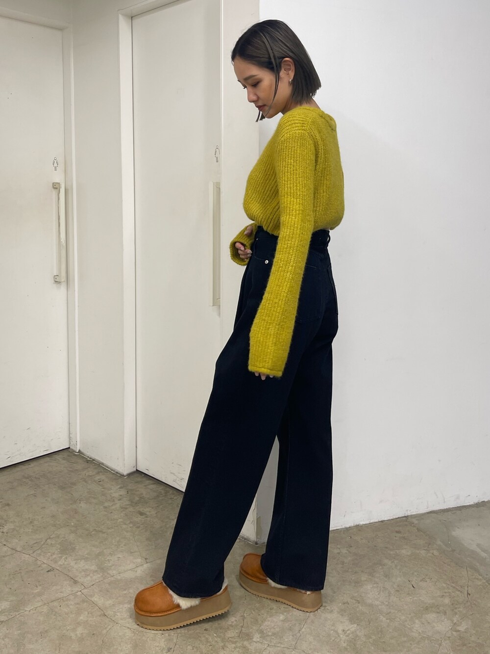 イエロー系のニット/セーター、ブラック系のデニムパンツ、ベージュ系のスリッポンを着用したレディースの秋コーディネートの3枚目の写真