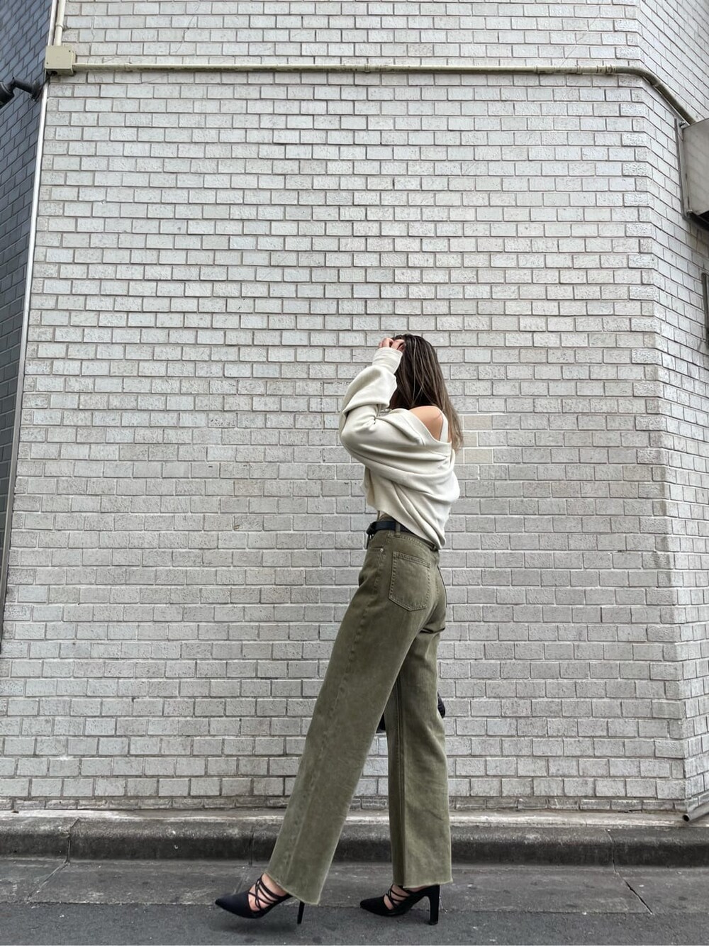 ブラック系のサンダル、ベージュ系のデニムパンツ、ブラック系のショルダーバッグを着用したレディースの秋コーディネートの2枚目の写真