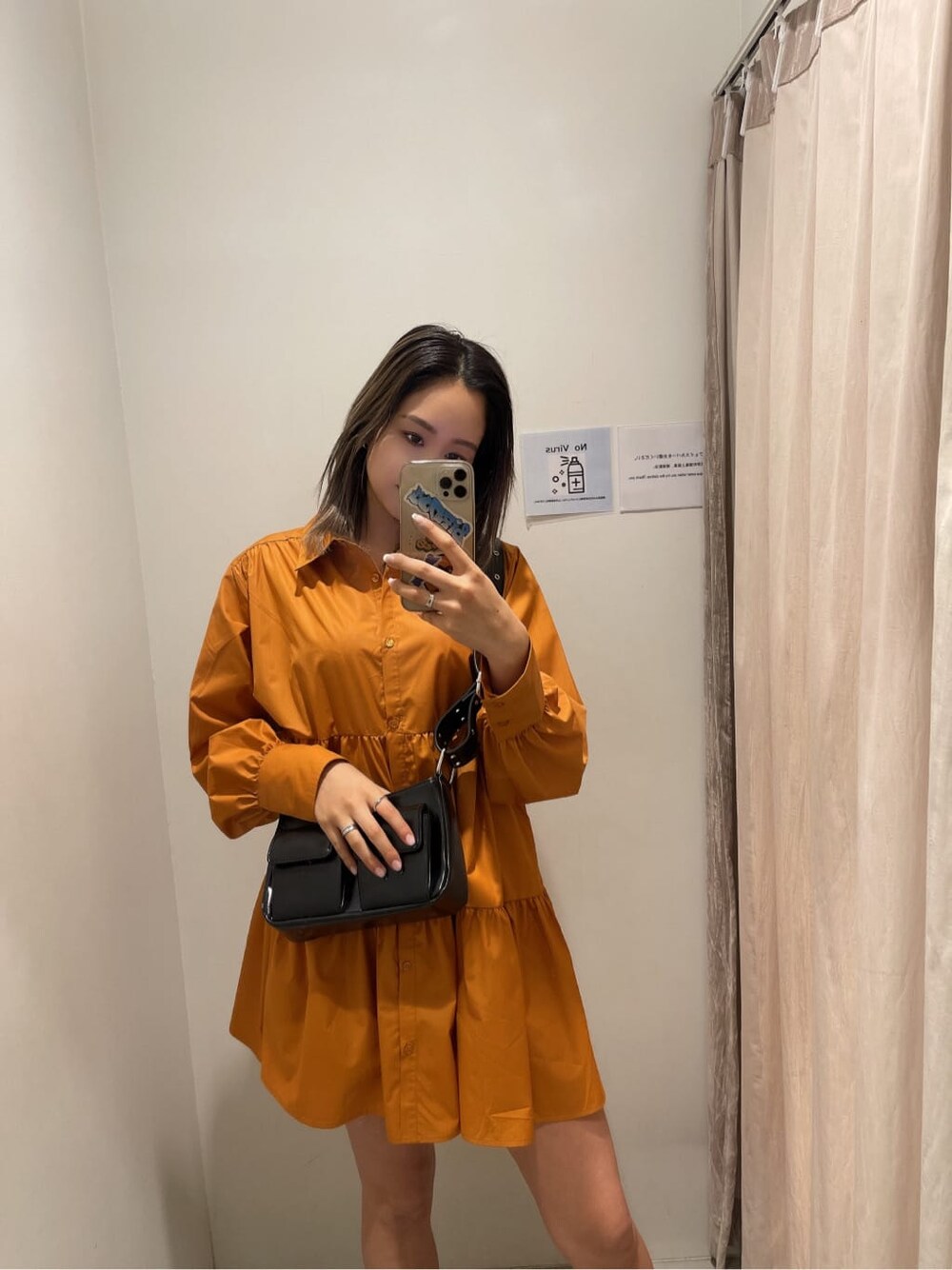 オレンジ系のシャツワンピース、ブラック系のブーツ、ブラック系のショルダーバッグを着用したレディースの冬コーディネートの3枚目の写真