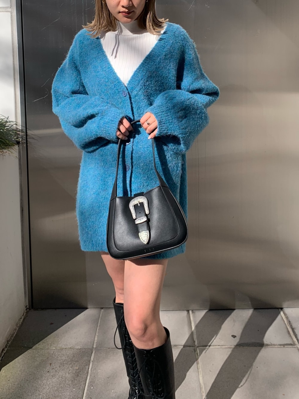 ブラック系のハンドバッグ、ブルー系のカーディガン/ボレロ、ホワイト系のTシャツ/カットソーを着用したレディースの冬コーディネートの5枚目の写真