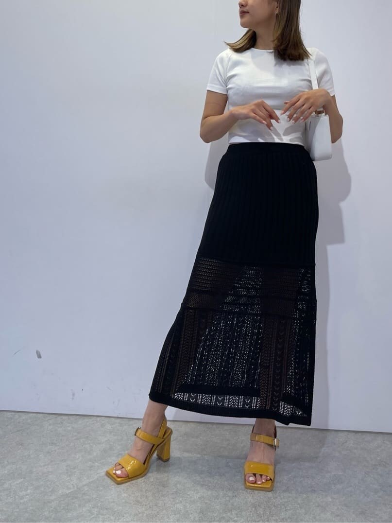 イエロー系のサンダル、ホワイト系のショルダーバッグ、ブラック系のスカートを着用したレディースの夏コーディネートの2枚目の写真