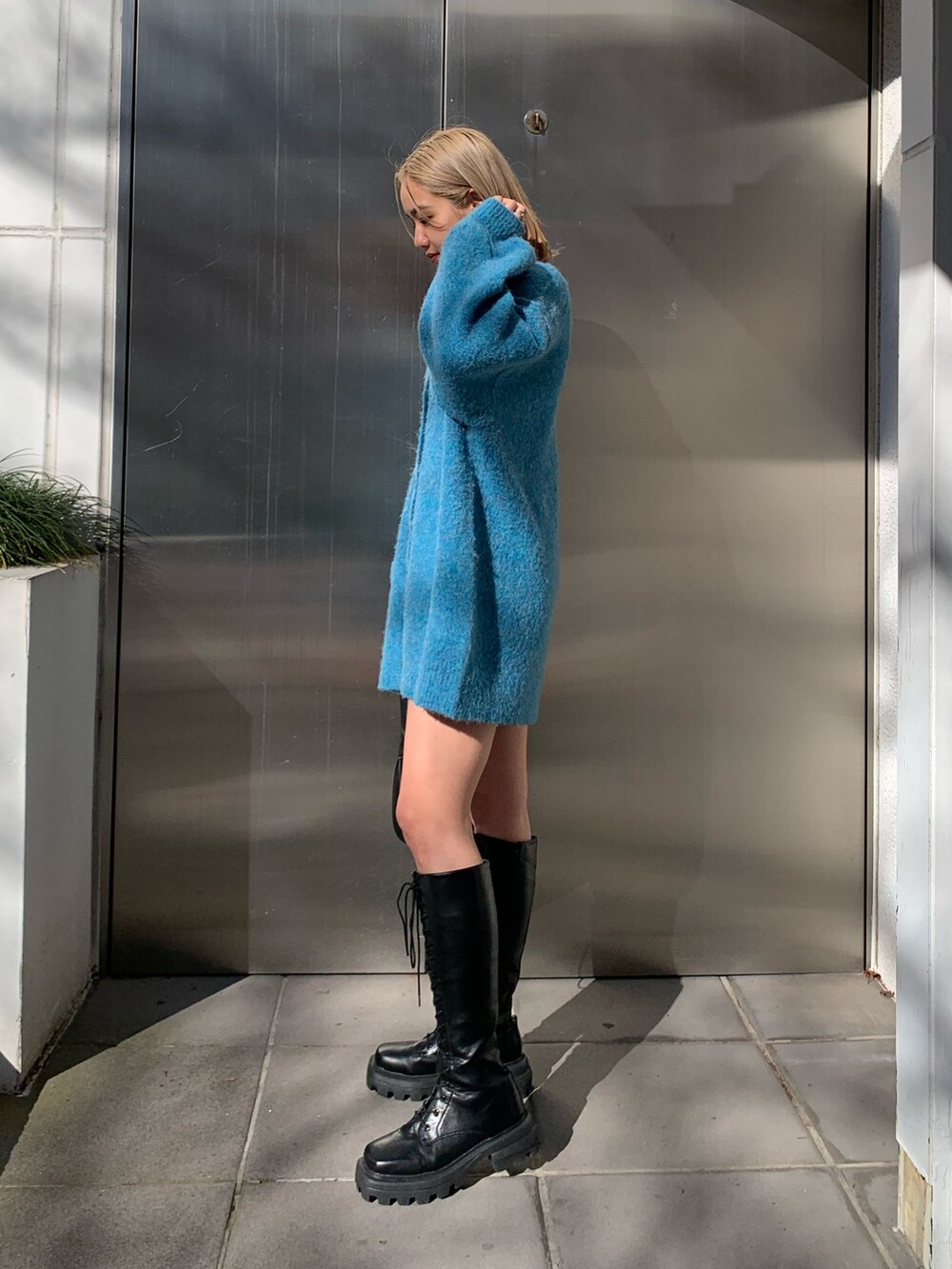 ブラック系のハンドバッグ、ブルー系のカーディガン/ボレロ、ホワイト系のTシャツ/カットソーを着用したレディースの冬コーディネートの2枚目の写真