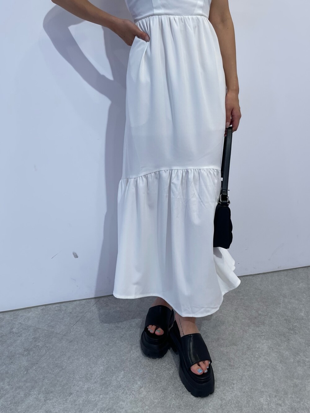 ホワイト系のワンピース、ブラック系のハンドバッグ、ブラック系のサンダルを着用したレディースの夏コーディネートの5枚目の写真