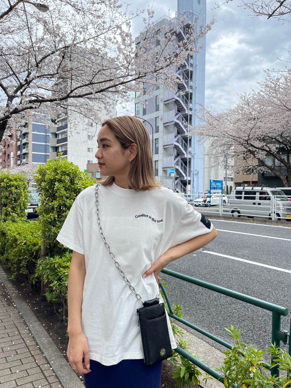 ブラック系のショルダーバッグ、ホワイト系のTシャツ/カットソー、ブルー系のスカートを着用したレディースの春コーディネートの6枚目の写真