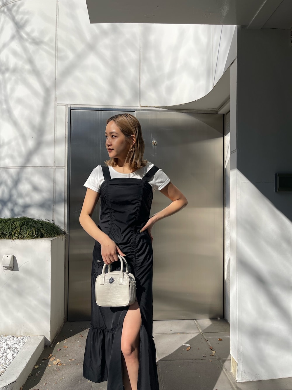 ブラック系のワンピース、ホワイト系のショルダーバッグ、ブラック系のブーツを着用したレディースの冬コーディネートの4枚目の写真