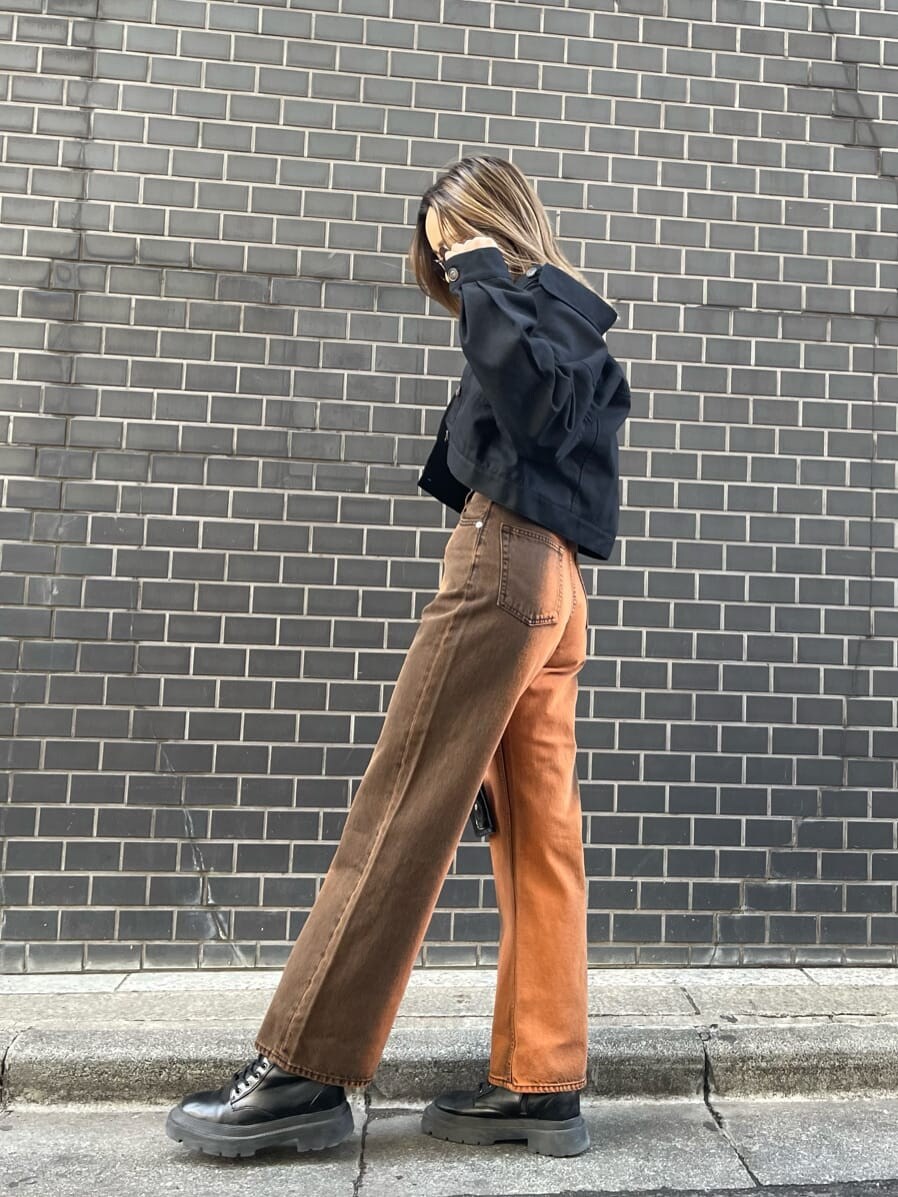 ブラック系のブルゾン、ブラック系のブーツ、ホワイト系のキャミソールを着用したレディースの春コーディネートの2枚目の写真