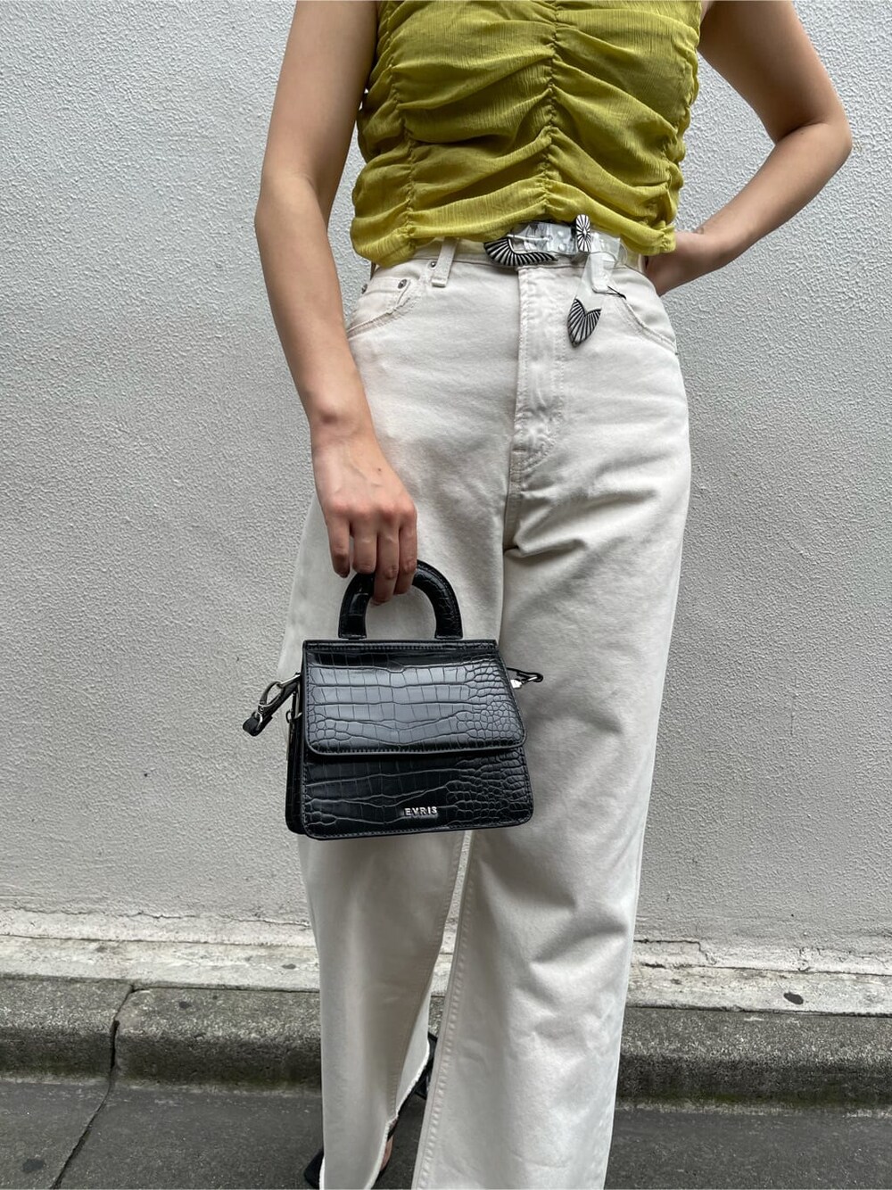 イエロー系のキャミソール、ホワイト系のデニムパンツ、ブラック系のサンダルを着用したレディースの夏コーディネートの6枚目の写真