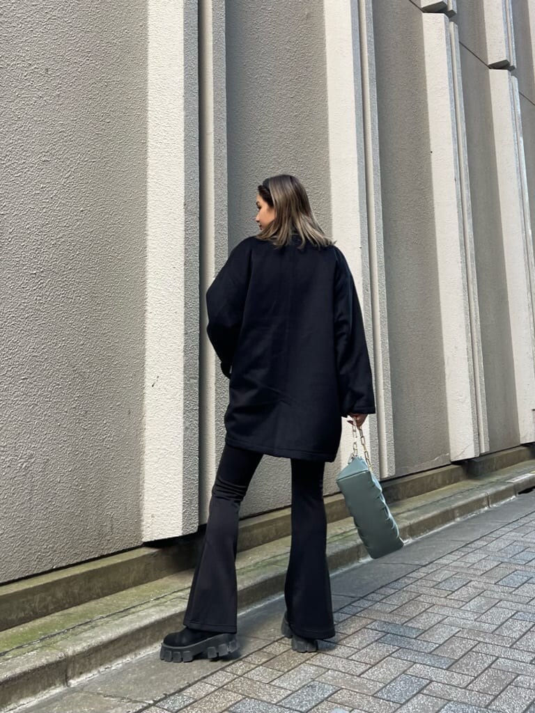 ブラック系のブーツ、ブラック系のその他アウター、グリーン系のショルダーバッグを着用したレディースの秋コーディネートの3枚目の写真