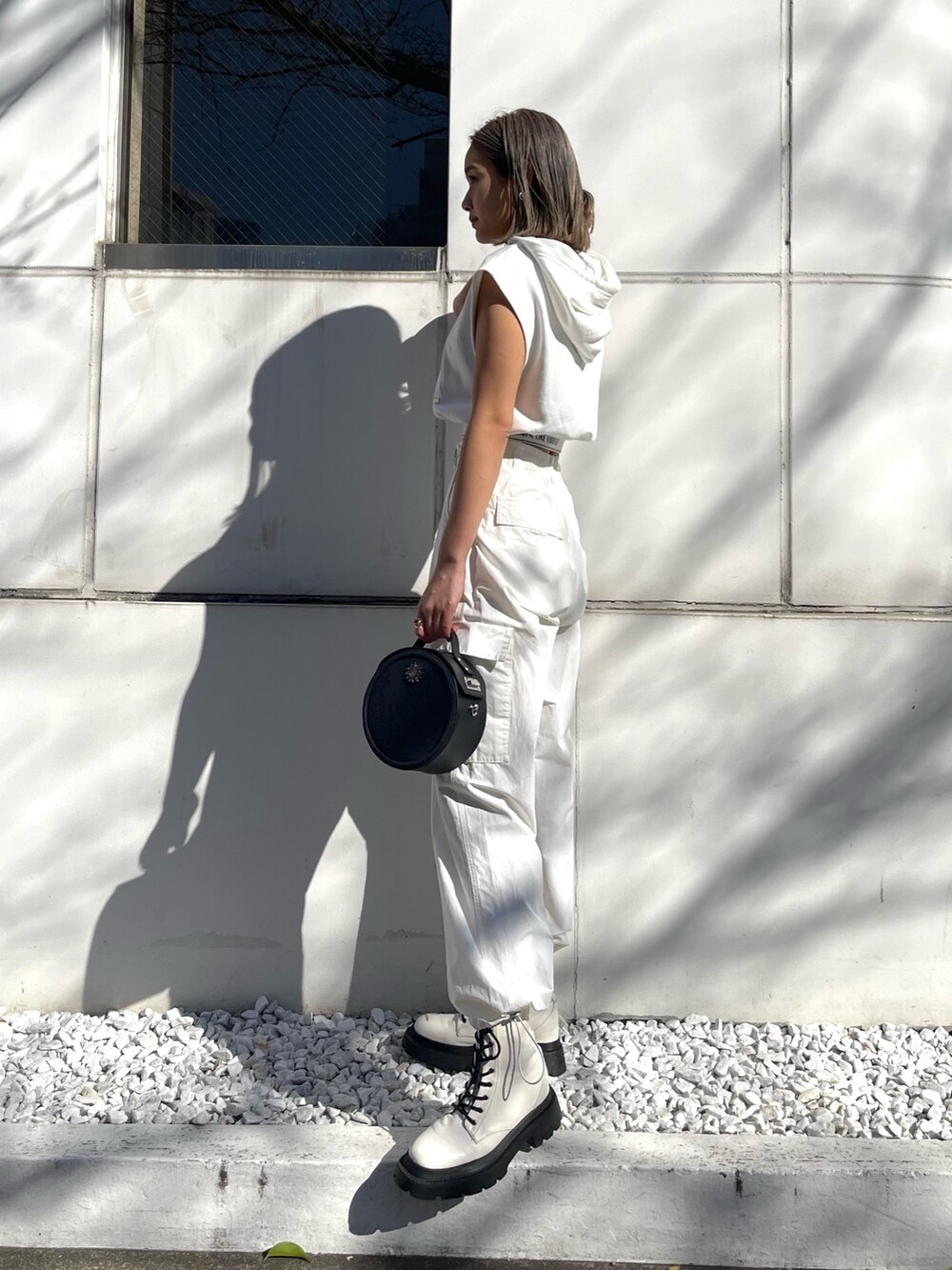ホワイト系のブーツ、ホワイト系のカーゴパンツ、ブラック系のショルダーバッグを着用したレディースの春コーディネートの2枚目の写真
