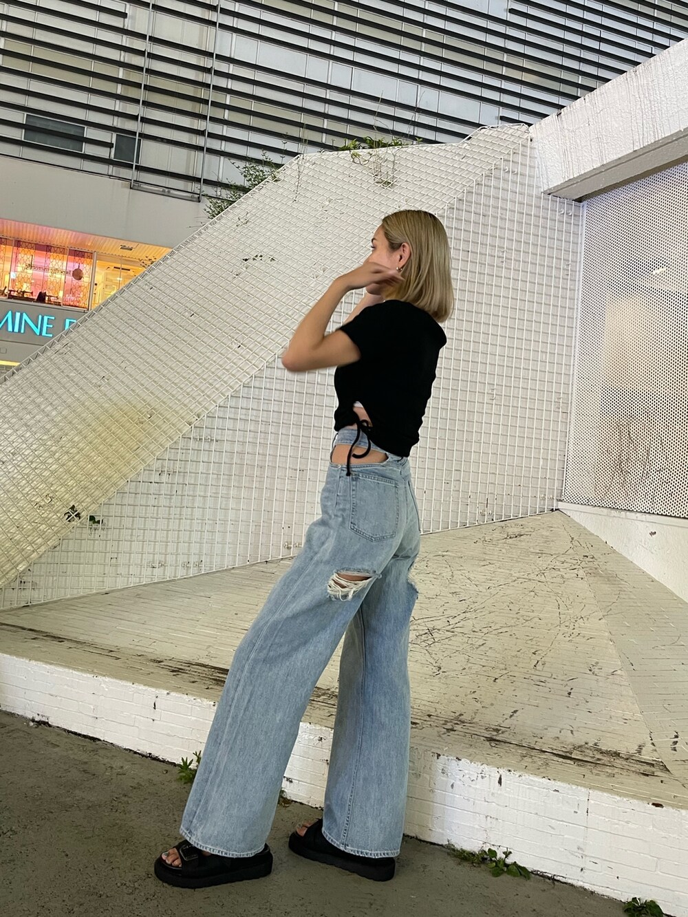 ブルー系のデニムパンツ、ブラック系のTシャツ/カットソー、ブラック系のサンダルを着用したレディースの夏コーディネートの5枚目の写真