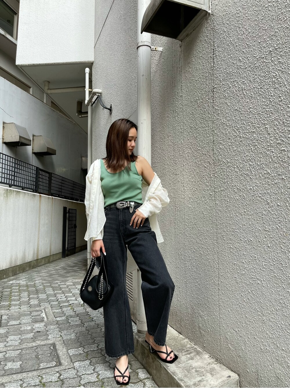 ブラック系のデニムパンツ、ホワイト系のシャツ/ブラウス、グリーン系のタンクトップを着用したレディースの春コーディネートの2枚目の写真
