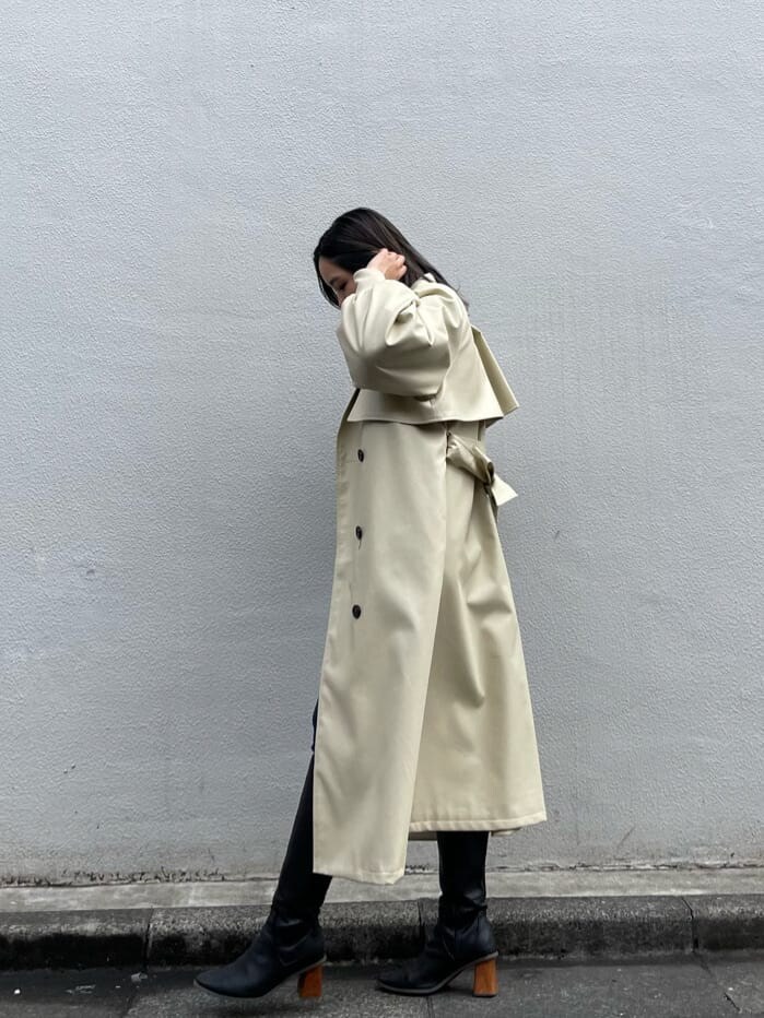 ブラック系のニット/セーター、ホワイト系のトレンチコート、ブラック系のブーツを着用したレディースの冬コーディネートの3枚目の写真