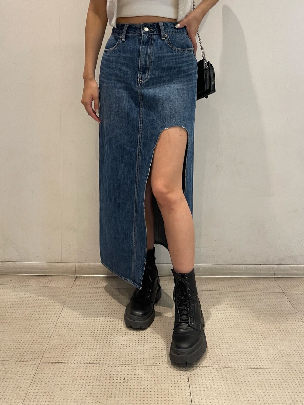 ブルー系のデニムスカート、ブラック系のブーツ、ホワイト系のキャミソールを着用したレディースの夏コーディネートの5枚目の写真