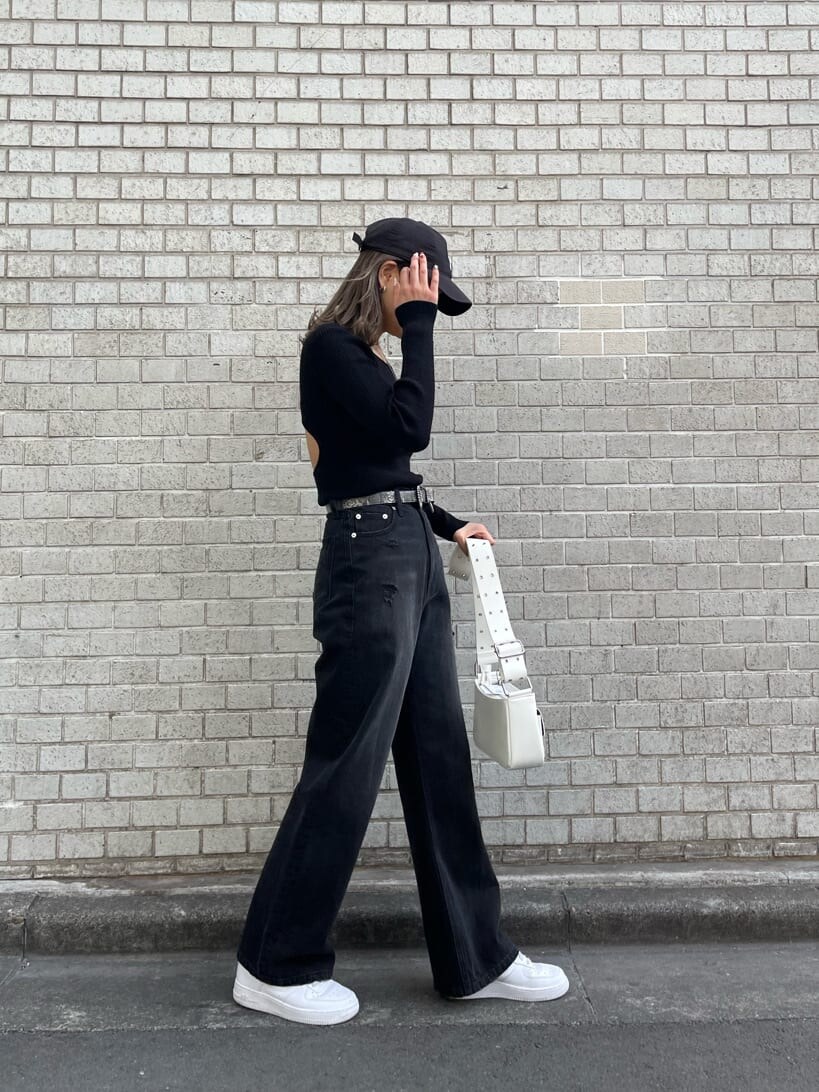 ブラック系のデニムパンツ、ブラック系のニット/セーター、ホワイト系のショルダーバッグを着用したレディースの冬コーディネートの2枚目の写真