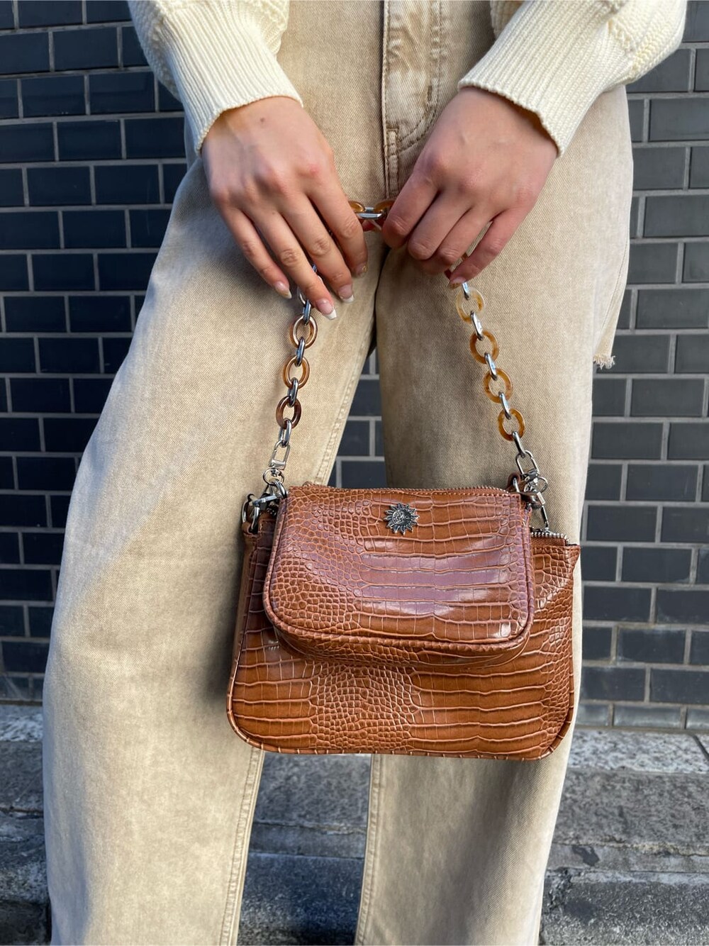 ベージュ系のデニムパンツ、ブラウン系のショルダーバッグ、ホワイト系のニット/セーターを着用したレディースの冬コーディネートの6枚目の写真