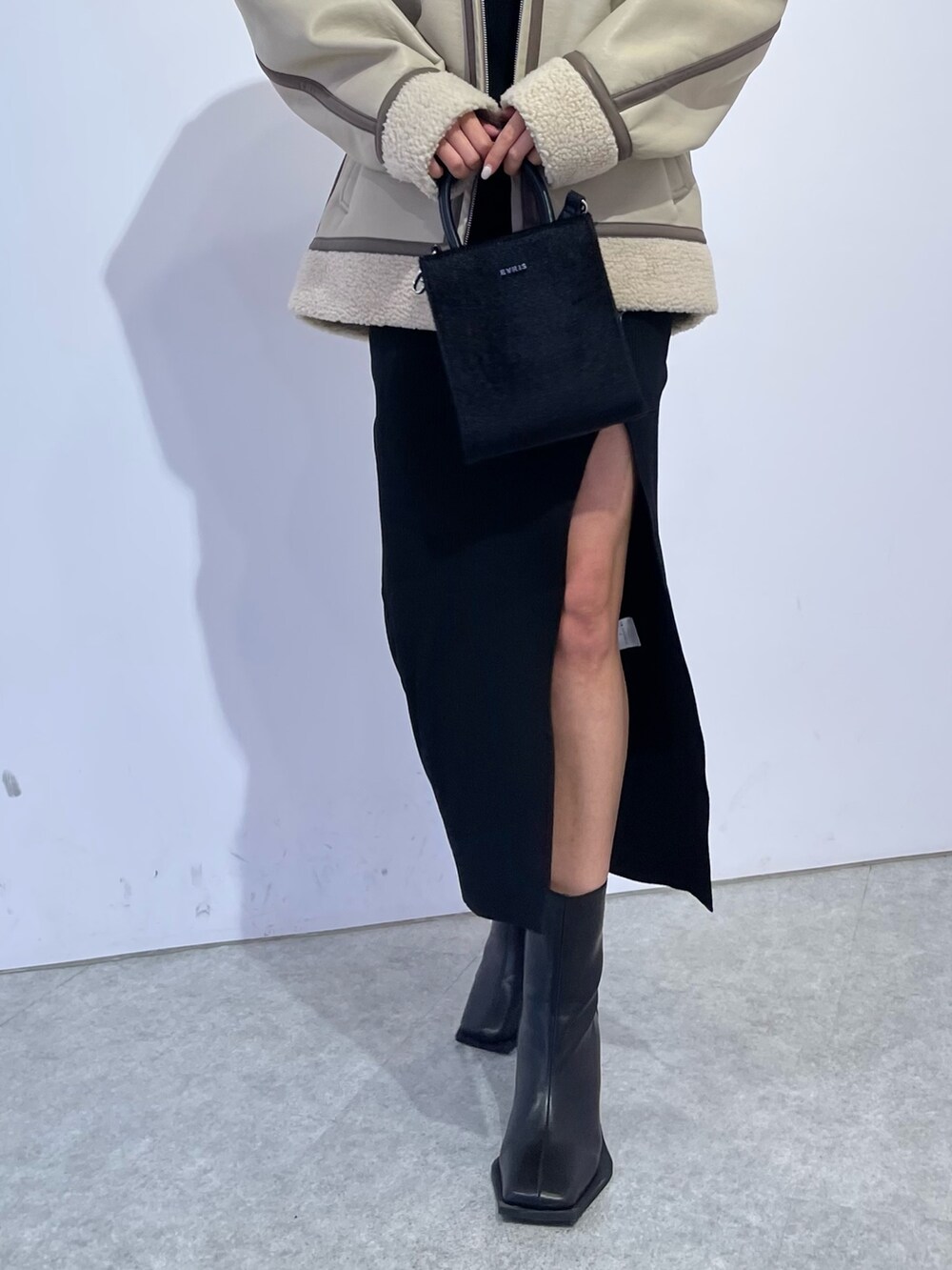 ブラック系のブーツ、ブラック系のショルダーバッグ、ブラック系のワンピースを着用したレディースの冬コーディネートの6枚目の写真