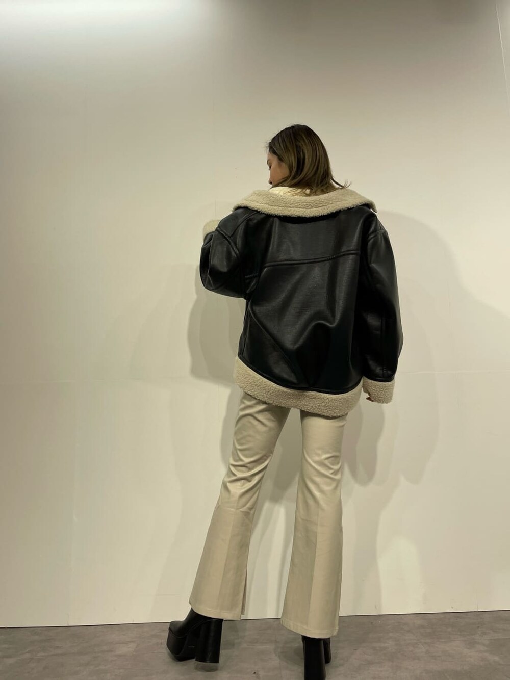 ブラック系のブルゾン、ブラック系のブーツ、ホワイト系のニット/セーターを着用したレディースの冬コーディネートの2枚目の写真