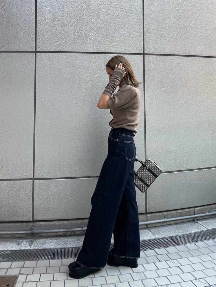 ブラック系のスリッポン、ブラック系のボストンバッグ、ブルー系のデニムパンツを着用したレディースの夏コーディネートの4枚目の写真