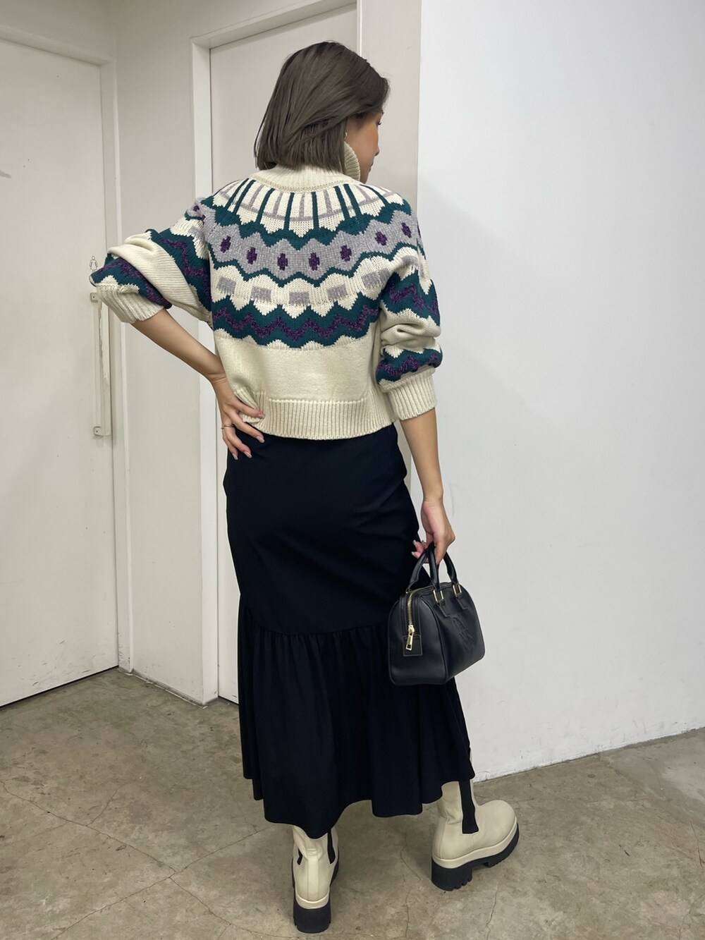 ブラック系のスカート、ホワイト系のブーツ、ホワイト系のニット/セーターを着用したレディースの秋コーディネートの3枚目の写真