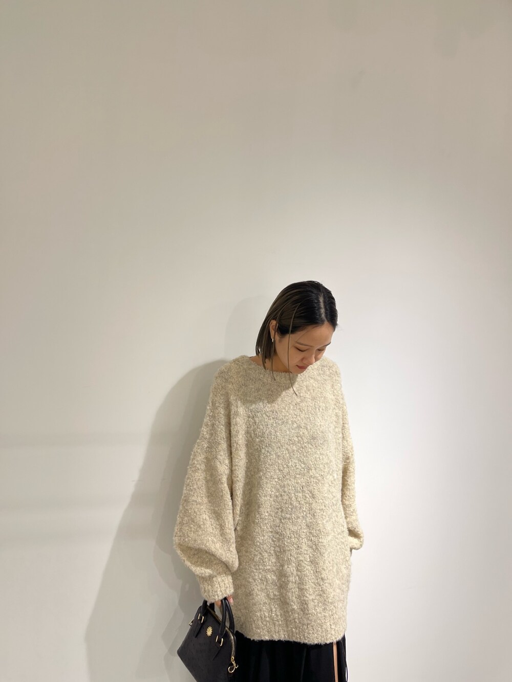 ブラック系のスカート、ホワイト系のブーツ、ブラック系のショルダーバッグを着用したレディースの秋コーディネートの9枚目の写真