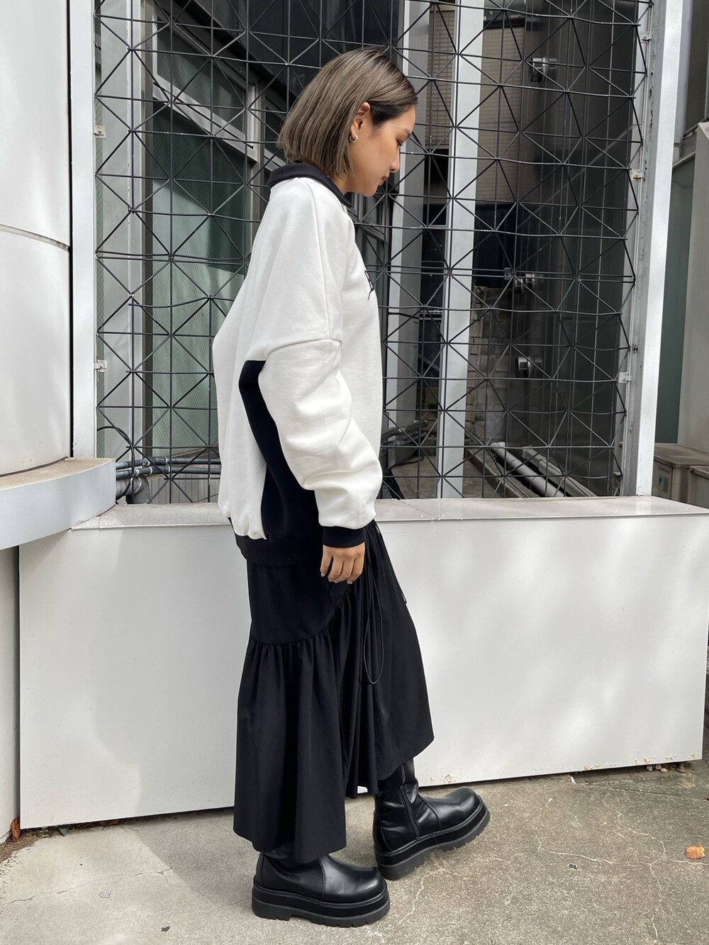 ホワイト系のスウェット、ブラック系のスカート、ブラック系のブーツを着用したレディースの秋コーディネートの4枚目の写真