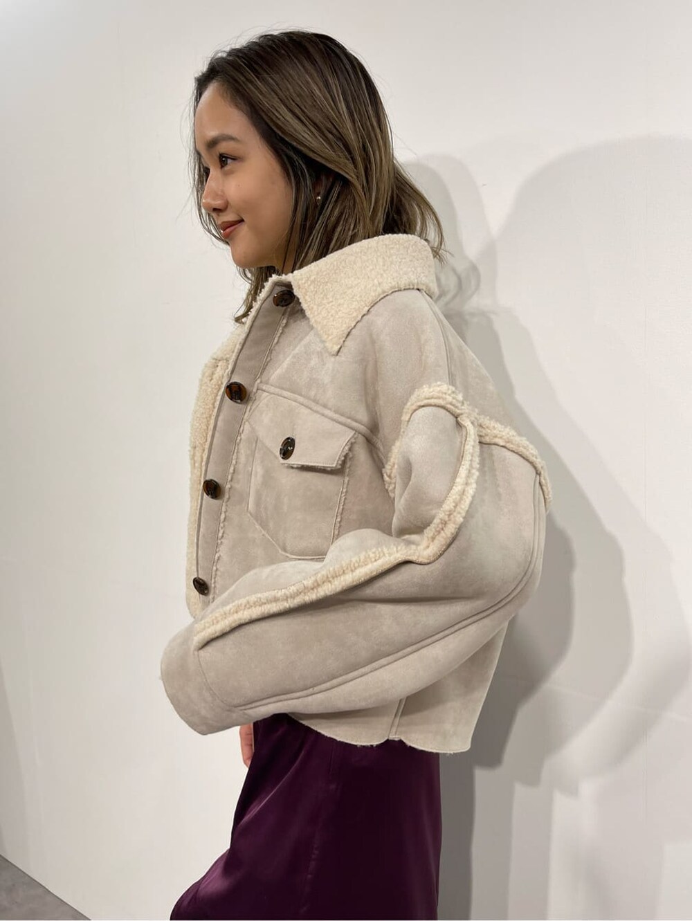 ブラック系のブーツ、ホワイト系のニット/セーター、パープル系のスカートを着用したレディースの秋コーディネートの6枚目の写真