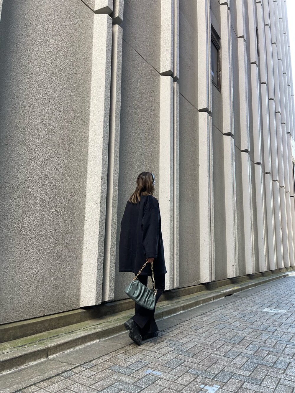 ブラック系のブーツ、ブラック系のその他アウター、グリーン系のショルダーバッグを着用したレディースの秋コーディネートの4枚目の写真