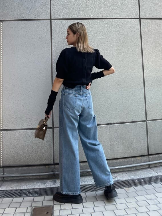 ブラック系のブーツ、ブラック系のニット/セーター、ブルー系のデニムパンツを着用したレディースの秋コーディネートの3枚目の写真