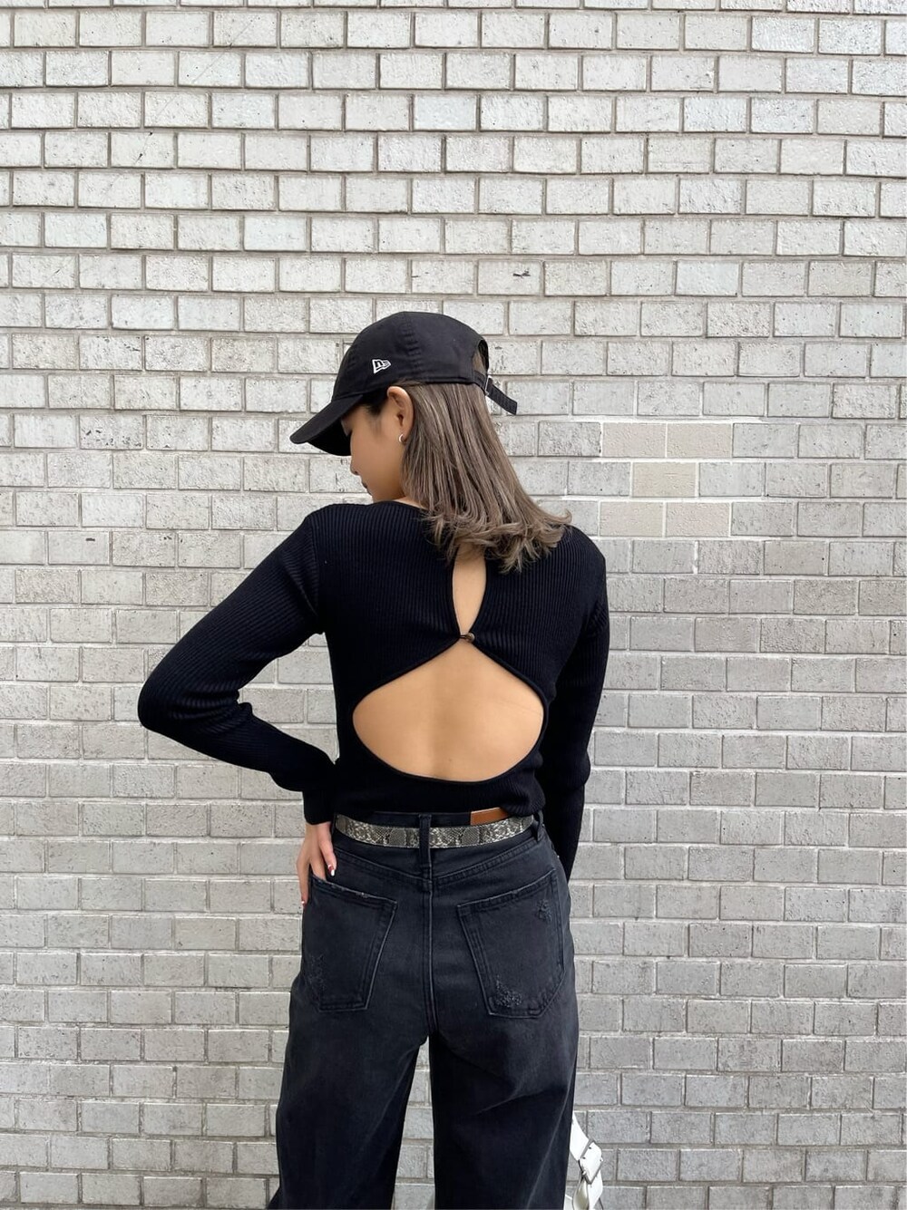 ブラック系のデニムパンツ、ブラック系のニット/セーター、ホワイト系のショルダーバッグを着用したレディースの冬コーディネートの8枚目の写真